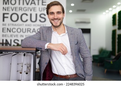 endearing young businessman in a business suit with a smile in the middle of the office