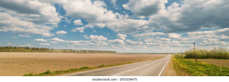 Endless country road to the horizon, fields and forest under cloudy sky. extra wide panoramic view
