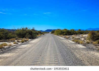 Endless Country Road Running Through The Barren Scenery Of The Death Valley National Park. Extreme Heat Haze On A Beautiful Hot Sunny Day With Blue Sky In Summer. Tourism And Vacations Concept. USA