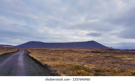 An Endless Road Leading To The Mountain Side. Colors Of Autumn. Road Is Empty, No Car Passing By. Grass On The Sides Of The Road Is Golden. Wilderness And Loneliness. Road Less Traveled.