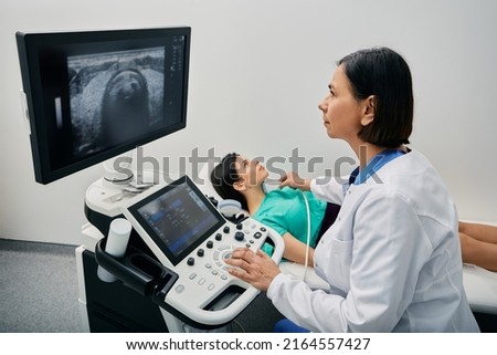 Endocrinologist making ultrasonography to female patient at ultrasound office of medical clinic. Ultrasound diagnostics of thyroid gland