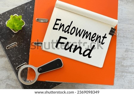 ENDOWMENT FUND text on notepad with pen, business concept. magnifying glass on orange tape