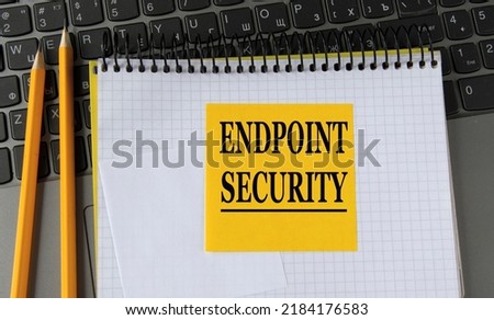 ENDPOINT SECURITY - words on a yellow piece of paper on the background of a laptop with a notebook and a pen. Business concept