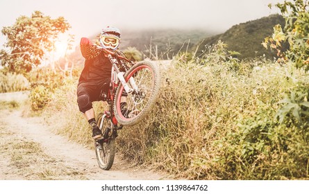 Enduro athlete doing wheelies outdoor with bike on hill track - Downhill rider skiding on mountain trail - Dangerous extreme sport concept - Focus on helmet - Shutterstock ID 1139864762