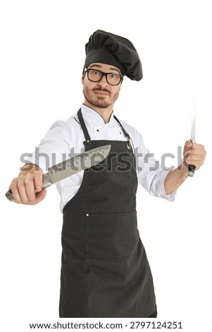 Energetic chef posing with kitchen knives in professional uniform and black apron isolated on a light background. Culinary expertise and restaurant concept.