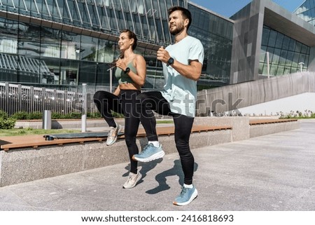 Energetic couple performing high-intensity workout in a modern urban area.