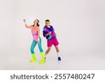 Energetic couple in retro sportswear dancing with joy against a white background, showcasing vibrant fashion