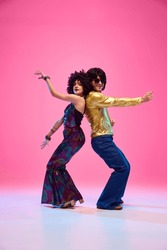 Energetic Disco Dance Lift, Couple In 1970s Fashion Outfit Dancing In Motion With Playful Energy Against Gradient Pink Studio Background. Concept Of American Culture, 1970s, 1980s Fashion, Music, Art