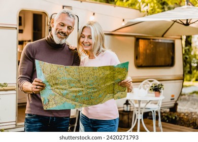 Energetic elderly european couple looking at the map with their caravan home behind. Travelers adventurers explorers reading the map for direction route destination - Powered by Shutterstock