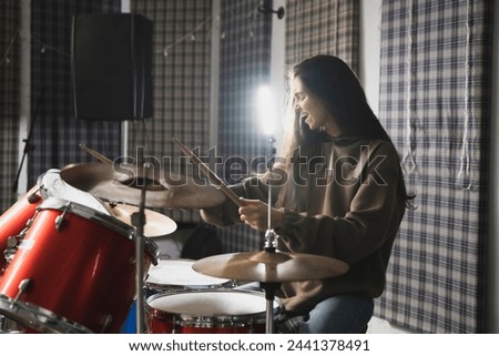 Energetic Female Drummer Enjoys Playing Red Drum Kit in a Casual Setting