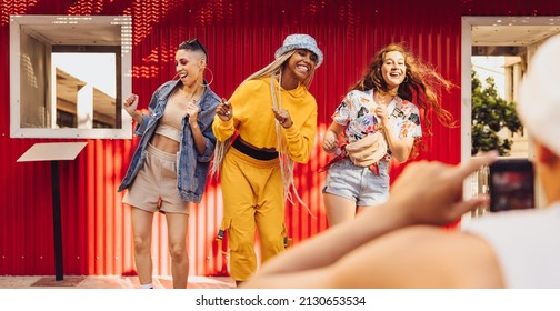 Energetic Female Friends Dancing In Front Of A Camera Phone Outdoors. Group Of Generation Z Friends Having Fun Together In The City. Vibrant Young People Creating Content For Their Social Media Vlog.