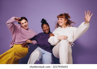 Energetic female friends dancing and having fun in casual clothing. Group of young women celebrating and having a good time against a studio background. Three best friends making cheerful memories. - Powered by Shutterstock