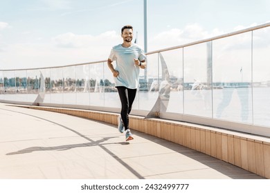 Energetic man in light blue t-shirt running on waterfront promenade with cityscape. - Powered by Shutterstock