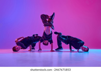 Energetic photo of young boys, in black attire dancing hip-hop in motion in mixed neo n light against vibrant gradient background. Concept of sport and hobby, music, fashion and art, movement. Ad - Powered by Shutterstock