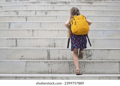 Energetic schoolgirl, braided hair and yellow backpack, ascending school steps