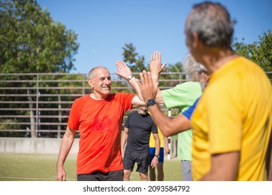 Energetic senior thanking each other after match. Men with grey hair in sport clothes standing in row on sport field, giving high fives. Football, sport, leisure concept - Powered by Shutterstock