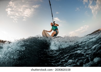 energetic sports man holds rope and catches a wave on wakesurf. Wakesurfing on the river. Summertime leisure - Powered by Shutterstock