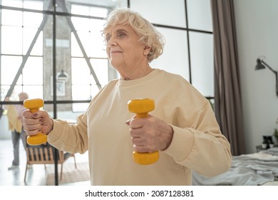 Energetic Sporty Mature Woman Exercising At Home, While Doing Bicep Curls