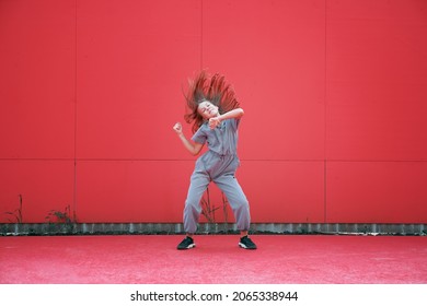 Energetic Teen Girl Dancing Waving Hair Outdoors By Red Wall. Dancer Performance. Contemporary Dance School Advertising