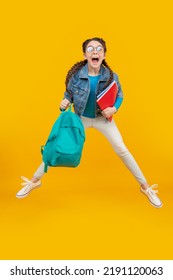 Energetic teenage girl screaming in midair, school. Excited girl jumping after school