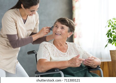 Energetic volunteer brushing pensioner's hair, preparing her for a family visit - Powered by Shutterstock