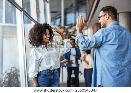 An energetic workplace moment capturing two colleagues exchanging a high five. The image conveys teamwork, success, and happiness, highlighting a positive and collaborative office environment.