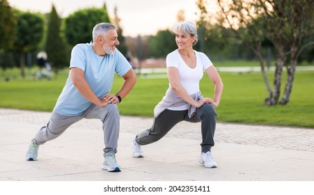 Energize your morning. Full length of active happy elderly family couple in sportswear working out together in city park in morning. Joyful senior husband and wife making sport outdoors, warming up - Powered by Shutterstock