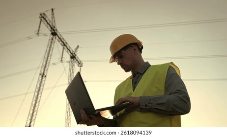 Energy auditor using portable computer during electricity pylon inspection