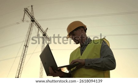 Energy auditor using portable computer during electricity pylon inspection
