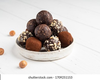Energy balls. Healthy raw dessert (bliss balls), vegetarian truffles, sugar free candies made of dates, hazelnuts, cocoa powder. Step by step cooking. White wooden background.  - Shutterstock ID 1709251153