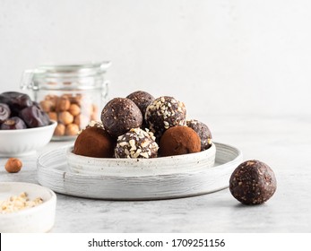 Energy balls. Healthy raw dessert (bliss balls), vegetarian truffles, sugar free candies made of dates, hazelnuts, cocoa powder. Step by step cooking. White wooden background. 