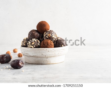 Energy balls. Healthy raw dessert (bliss balls), vegetarian truffles, sugar free candies made of dates, hazelnuts, cocoa powder. Step by step cooking. White wooden background. 