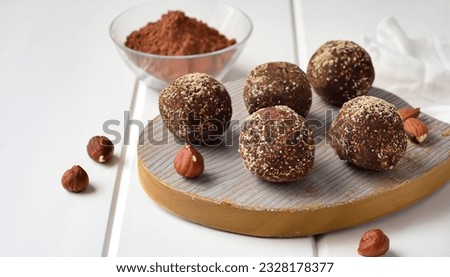 Energy balls. Healthy raw dessert (bliss balls), vegetarian truffles, sugar free candies made of dates, hazelnuts, cocoa powder. Step by step cooking. White wooden background.