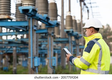 Energy business technology industry concept. Electrical engineer studying reading on tablet. Electrical worker engineer working with digital tablet near tower with electricity