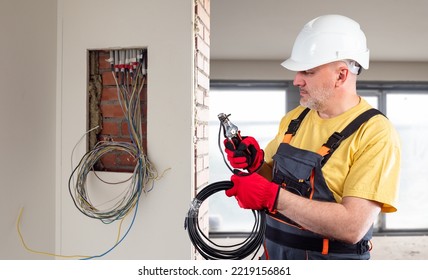 Energy Company Employee. Man Electrician With Wires. Builder Stretches Wiring. Man Builder Works With Electricity. Preparation Of Electrical Wiring During Construction. Portrait Of Repairman Man