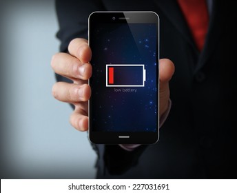 Energy Concept: Male Hand Holding A Low Battery Mobile Phone 