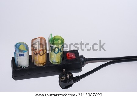 Energy consumption and increase in electricity prices three Euro bills in a power strip and a plug left bottom view with a gray background