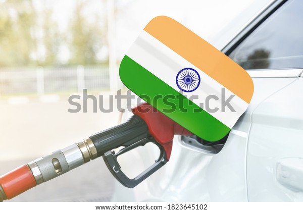 Energy and economy\
concept. Flag of India on the car\'s fuel filler flap with gas pump\
nozzle in the tank.