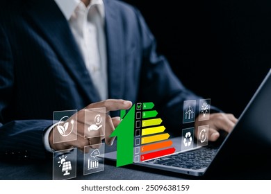 Energy efficiency concept. Businessman using laptop with energy efficiency rating symbol on virtual screen for energy efficient house building rate label audit. - Powered by Shutterstock