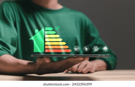 Energy efficiency concept. Person using tablet with energy efficiency rating icon on virtual screen for energy efficient house building rate label audit. - Powered by Shutterstock