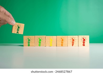 Energy efficiency and home improvement concept. Ecological and bio energetic house. Energy class;house efficiency rating. Low energy to save money. Hand holds wooden cubes with energy efficiency scale - Powered by Shutterstock