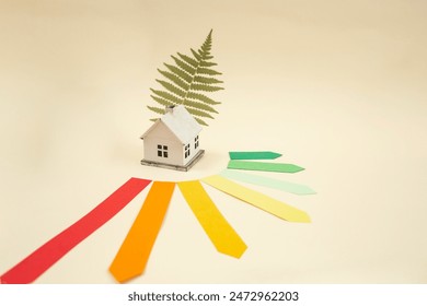 Energy efficiency rating chart, model miniature house and green fern leaf on beige background - Powered by Shutterstock