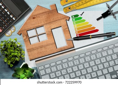 Energy efficiency rating graph on a desk with a wooden house model, calculator, folding ruler, drawing compass, pencil and a computer keyboard - Powered by Shutterstock