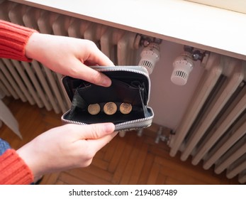 Energy and heating bills, concept. Poverty and the gas crisis. Hands hold a wallet with money in front of the radiator.
