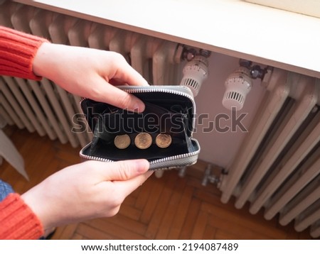 Energy and heating bills, concept. Poverty and the gas crisis. Hands hold a wallet with money in front of the radiator.