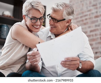 The Energy Housed In My Favourite Person. Shot Of A Mature Couple Going Through Paperwork On The Sofa At Home Together.