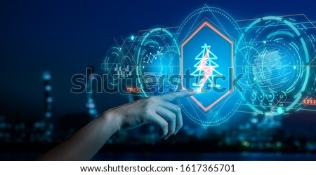 Energy and  power plant concept.Human hand holding a icon electric bolt on blurry bokeh power plant background.Industry 4.0 concept image.