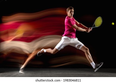 Energy, power. Young man, male tennis player in white pink sportwear playing tennis in mixed neon light on dark background. Concept of motion, force, speed, healthy lifestyle, professional sport.