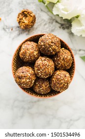 Energy protein balls with healthy ingredients on marble table. Home made with dates, peanut butter, flax and chia seeds, oats, almond and chocolate drops
