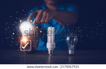 Energy saving concept, Fluorescent bulb, incandescent lamp and LED bulb, Human hand holding and touch for select LED light bulb for best power saving, Electricity conservation.